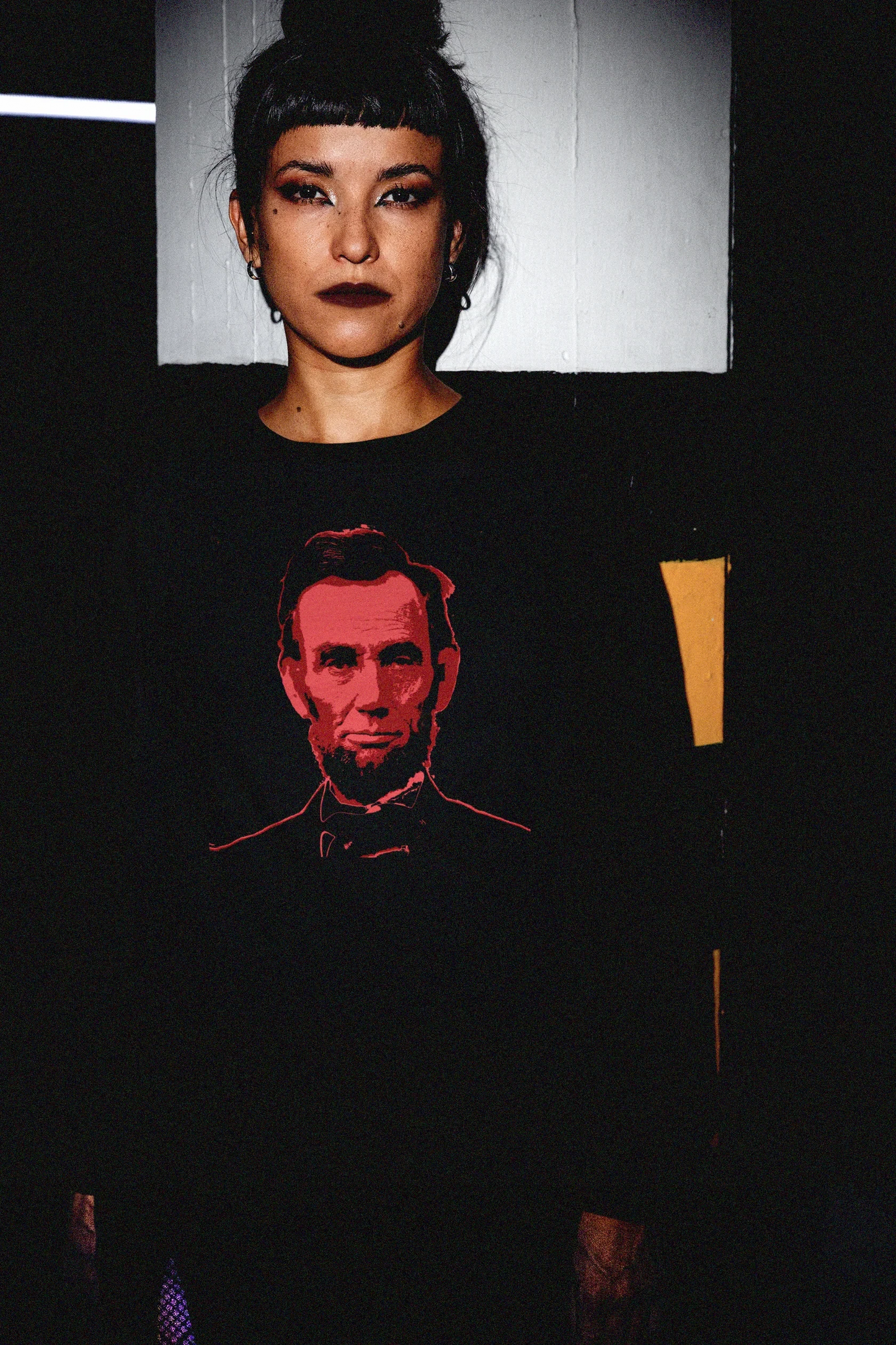 Goth Chick in Parking_Garage with Bun wearing a Long Sleeve Jersey depicting Abraham Lincoln | Blood of the Union. Abraham Lincoln wasn’t a saint dropped from the heavens—he was a messy, pragmatic politician shaped by the rough-and-tumble Free Soil movement and the hard edges of frontier republicanism. The perfect gift for the history major or American radical in your life. Bella+Canvas 3501 Long Sleeve Jersey #EUTC