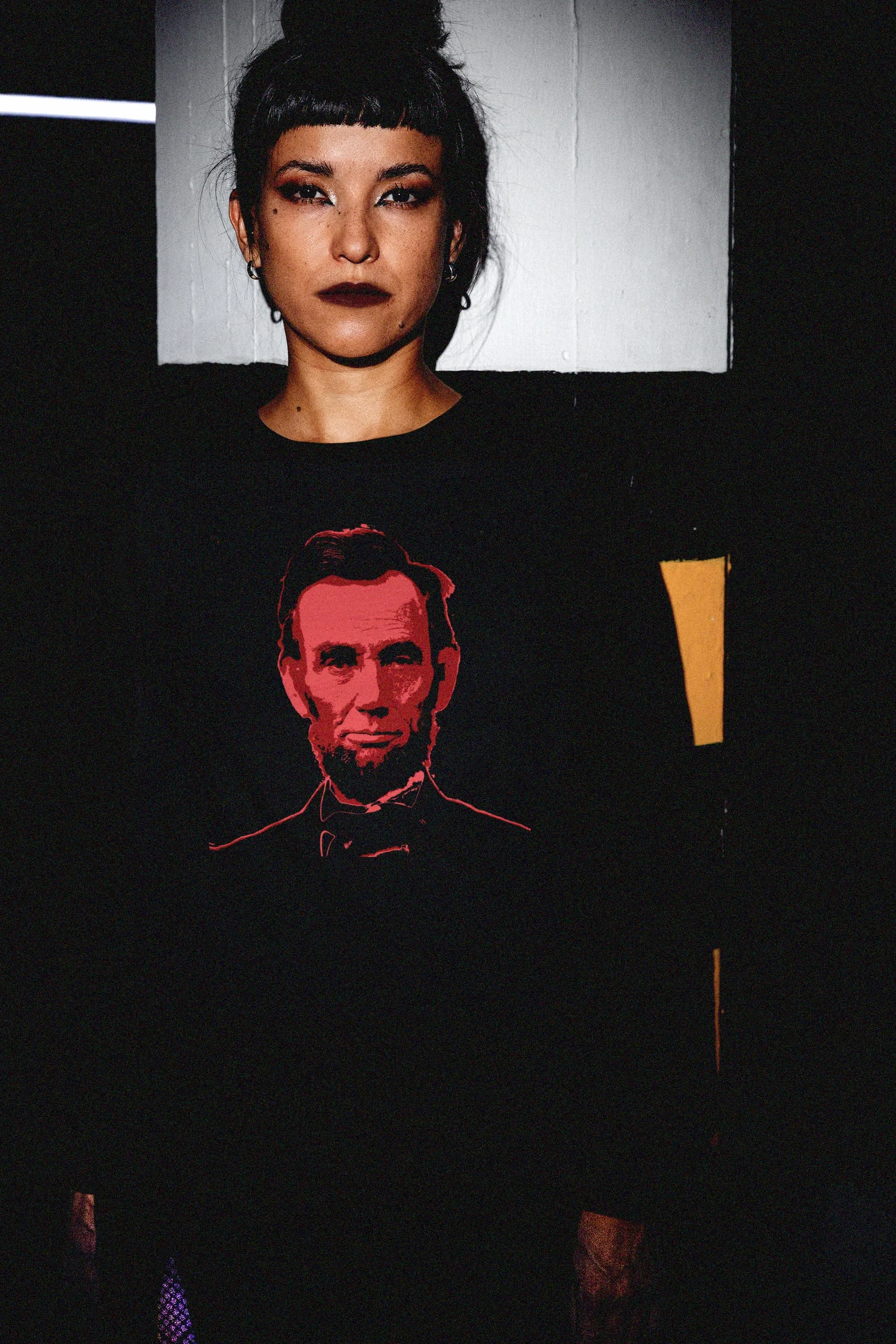 Goth Chick in Parking_Garage with Bun wearing a Long Sleeve Jersey depicting Abraham Lincoln | Blood of the Union. Abraham Lincoln wasn’t a saint dropped from the heavens—he was a messy, pragmatic politician shaped by the rough-and-tumble Free Soil movement and the hard edges of frontier republicanism. The perfect gift for the history major or American radical in your life. Bella+Canvas 3501 Long Sleeve Jersey #EUTC