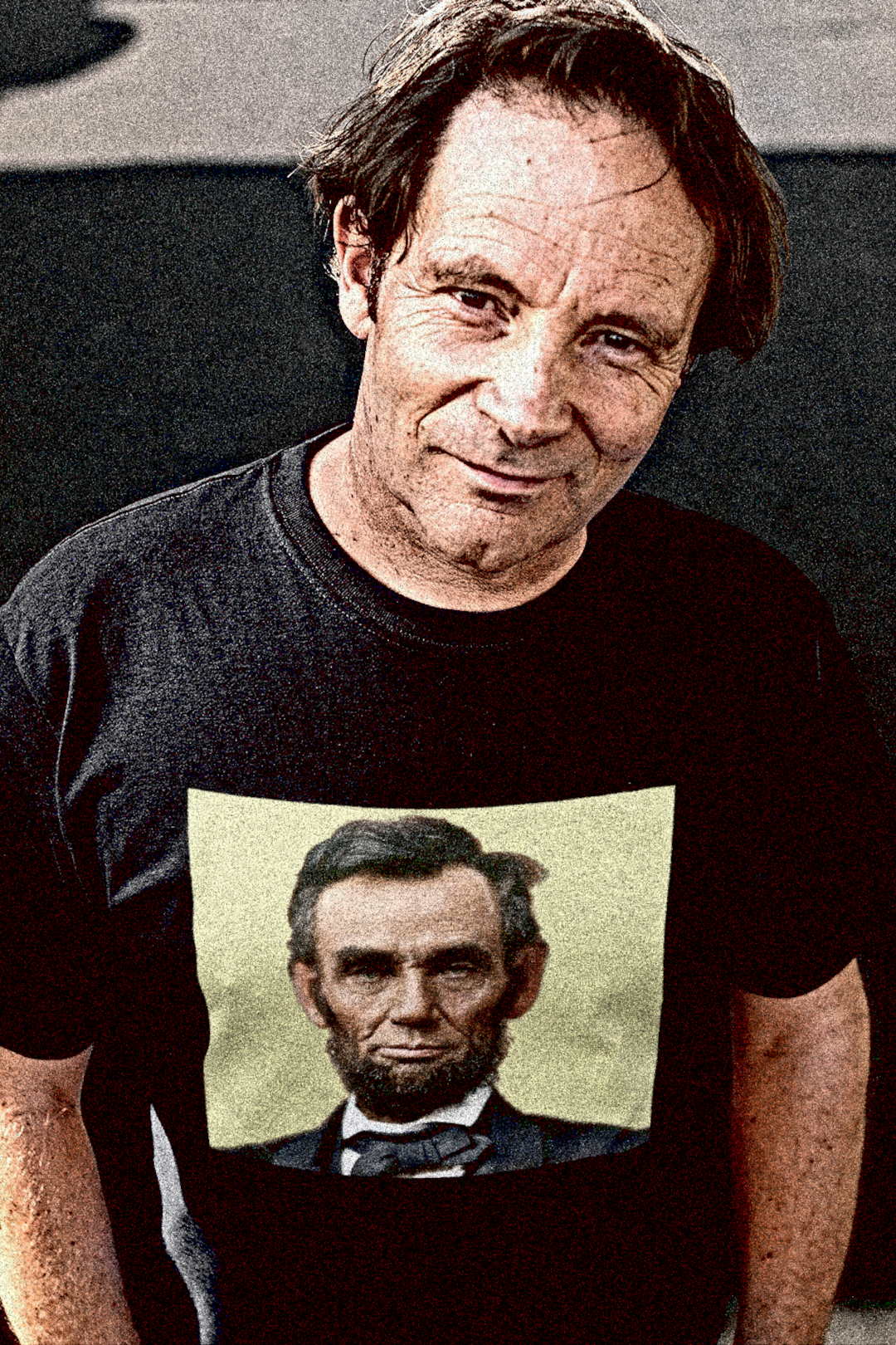 Tough middle aged White guy looking up from street wearing a Basic Black T-Shirt with khaki colorized portrait of Abraham Lincoln. From his Second Inaugural Address, delivered near the end of the Civil War, Lincoln’s words capture the nation’s moral high point amid its deepest wound. Great gift for American radicals and history buffs. Bella+Canvas 3001 Basic T-Shirt #EUTC
