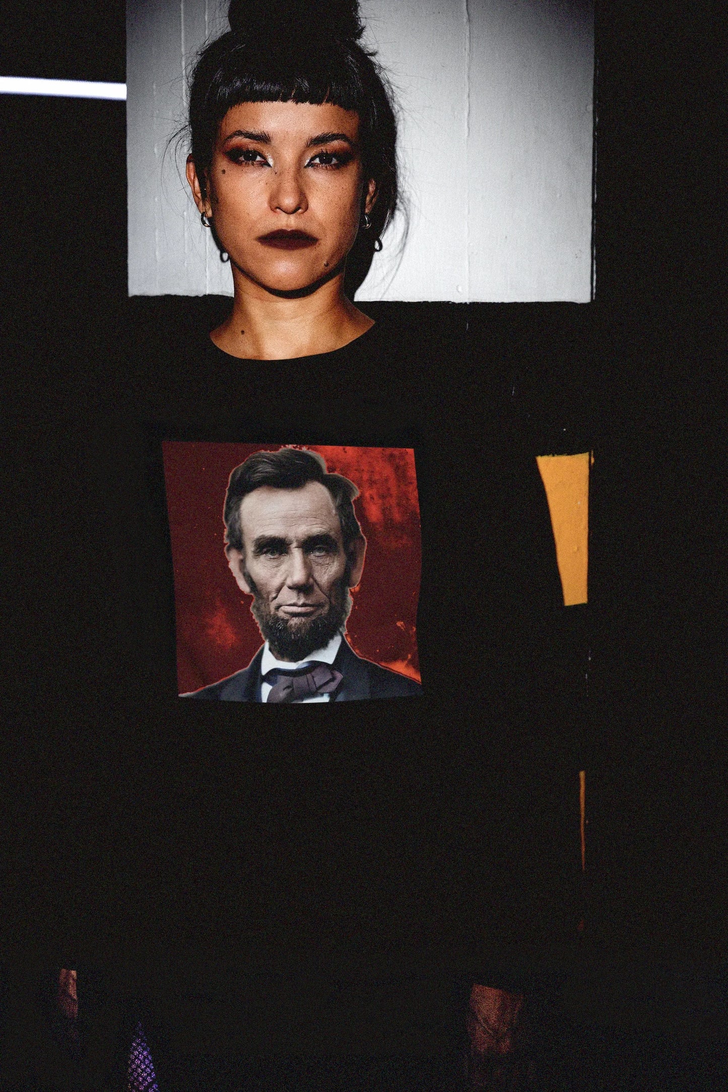 Goth Chick in Parking Garage with Bun wearing  Long Sleeve Jersey depicting a colorized Abraham Lincoln | The Country Burns. Abraham Lincoln wasn’t a saint dropped from the heavens—he was a messy, pragmatic politician shaped by the rough-and-tumble Free Soil movement and the hard edges of frontier republicanism. The perfect gift for the history major or American radical in your life. Bella+Canvas 3501 Long Sleeve Jersey #EUTC