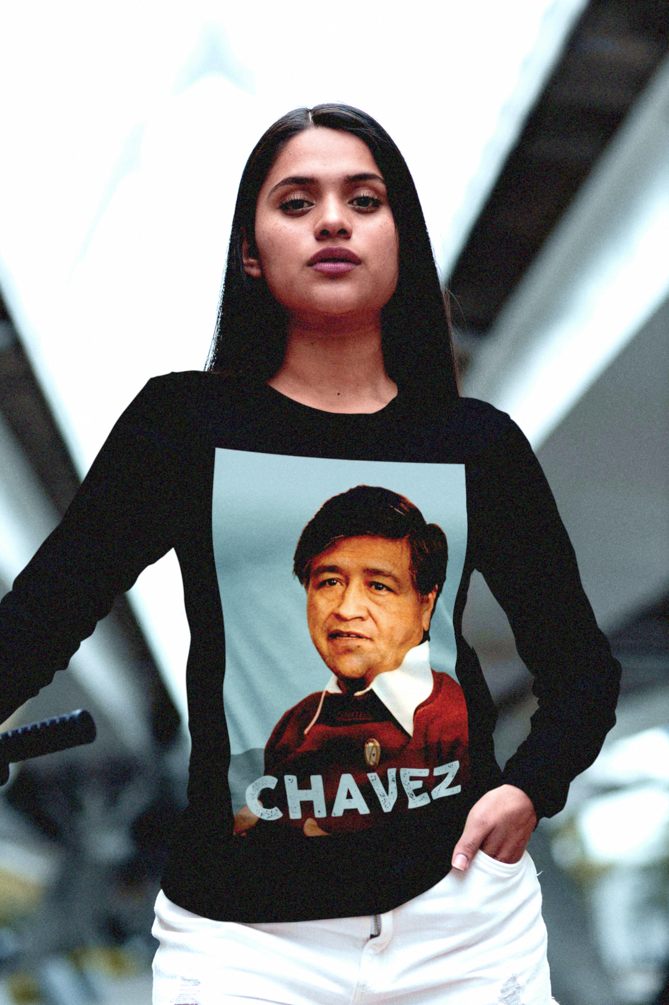 Strong, young Latina woman with mountain bike in an urban setting wearing a Long Sleeve Jersey depicting Cesar Chavez. Labor leader and civil rights activist Cesar Chavez (1927–1993) co-founded the United Farm Workers, transforming the struggle of migrant laborers into a national movement for dignity and fair wages. Perfect gift for Latino activists and labor organizers. Bella+Canvas 3501 #EUTC