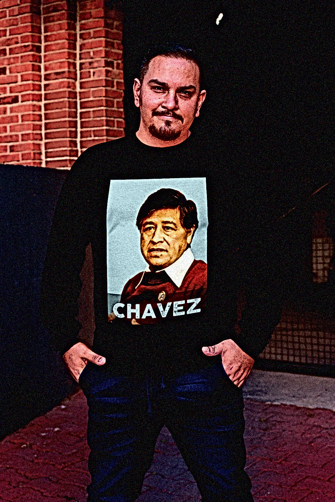 Latino union organizer on a loading dock wearing Long Sleeve Jersey depicting Cesar Chavez. Labor leader and civil rights activist Cesar Chavez (1927–1993) co-founded the United Farm Workers, transforming the struggle of migrant laborers into a national movement for dignity and fair wages. Perfect gift for Latino activists and labor organizers. Bella+Canvas 3501 #EUTC