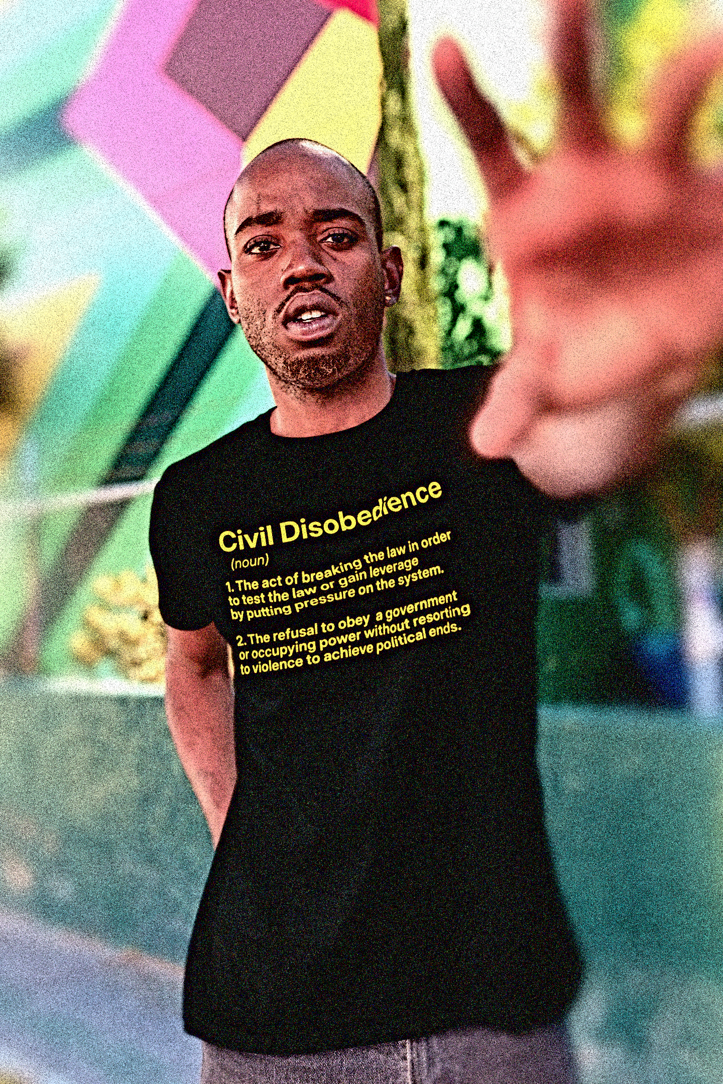 Black man in Miami block a photographer in front of a mural wearing a Basic Black T-Shirt with the definition for CIVIL DISOBEDIENCE (noun) 1. The act of breaking the law in order to test the law or gain leverage by putting pressure on the system. 2. The refusal to obey a government or occupying power without resorting to violence to achieve political ends. 

Perfect gift for the political outlaw in your life. Protesters and activists. Cotton Bella+Canvas 3001 #EUTC