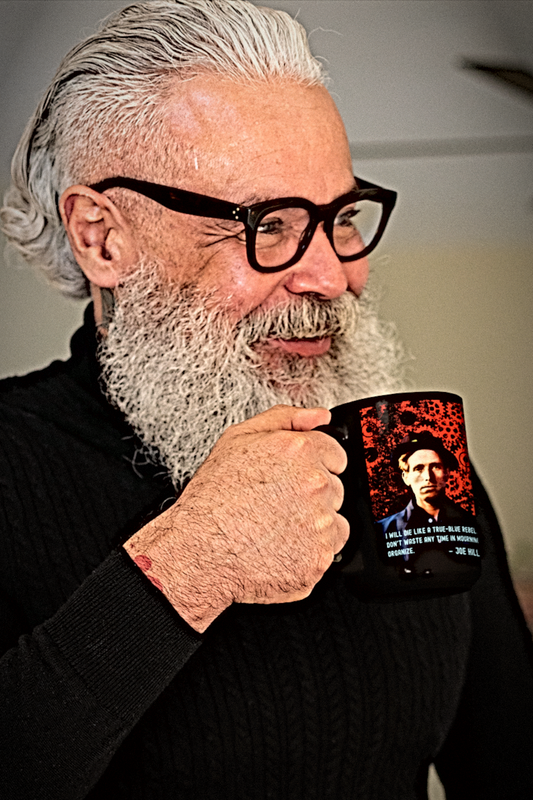 Joe Hill Mug: Hip older man with  beard and thick black glasses holding Joe Hill Wobbly IWW mug