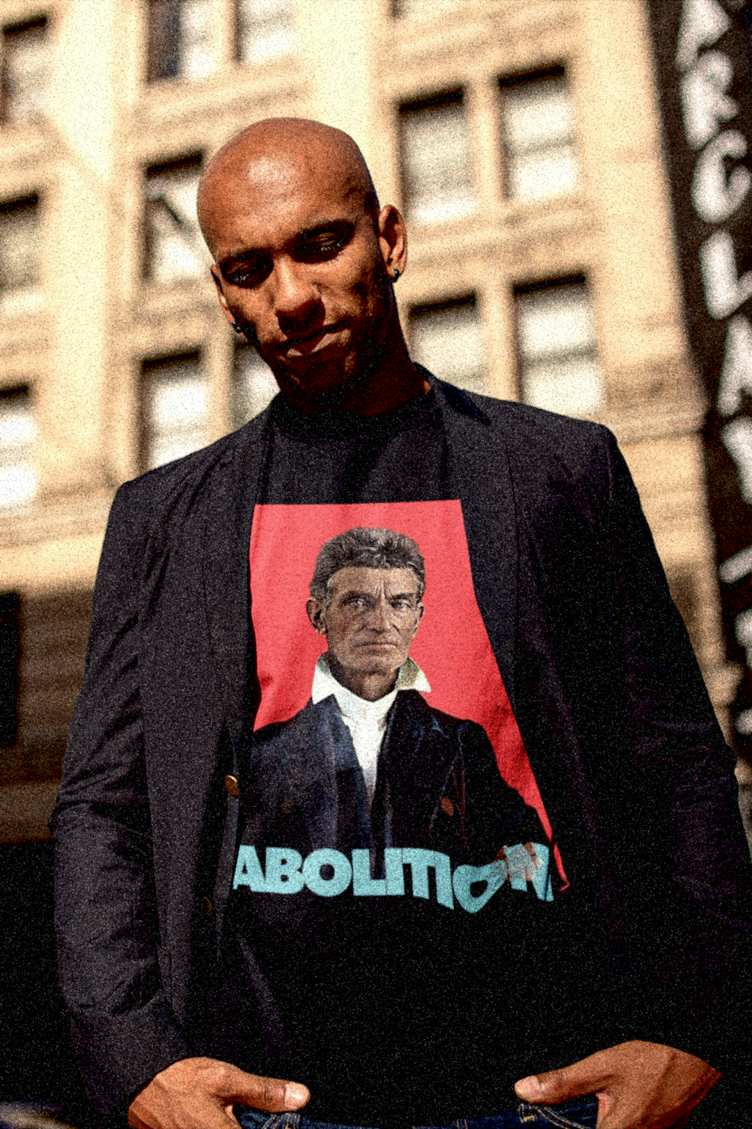 John Brown - Abolition - Bald Black Man in Sport Coat in the City wearing wearing Basic Black T-Shirt: John Brown, militant abolitionist who fought slavery with uncompromising zeal and sacrifice. Cotton Bella+Canvas 3001 #EUTC