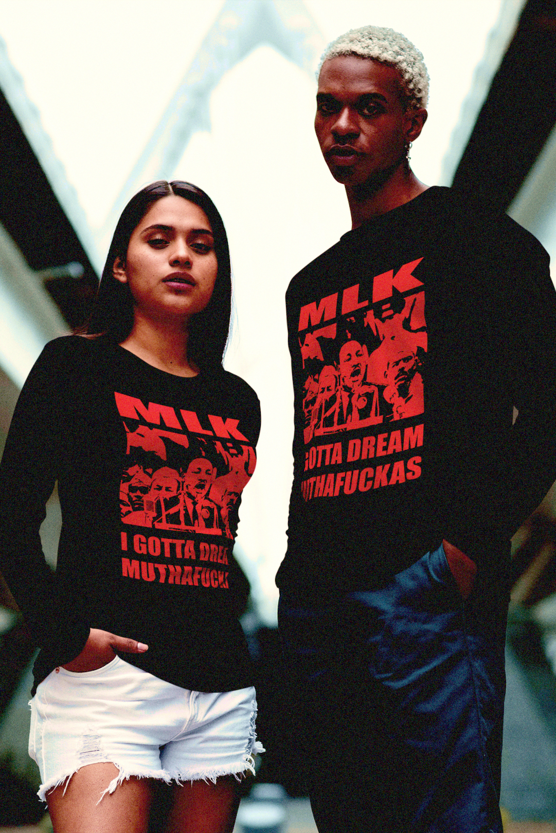 Hip Latina and Black man couple wearing red on black cotton long sleeve jerseys of MLK: I GOTTA DREAM MUTHAFUCKAS an irreverent take on the famous I Have a Dream Speech. Great gift for Black Lives Matter activist.
