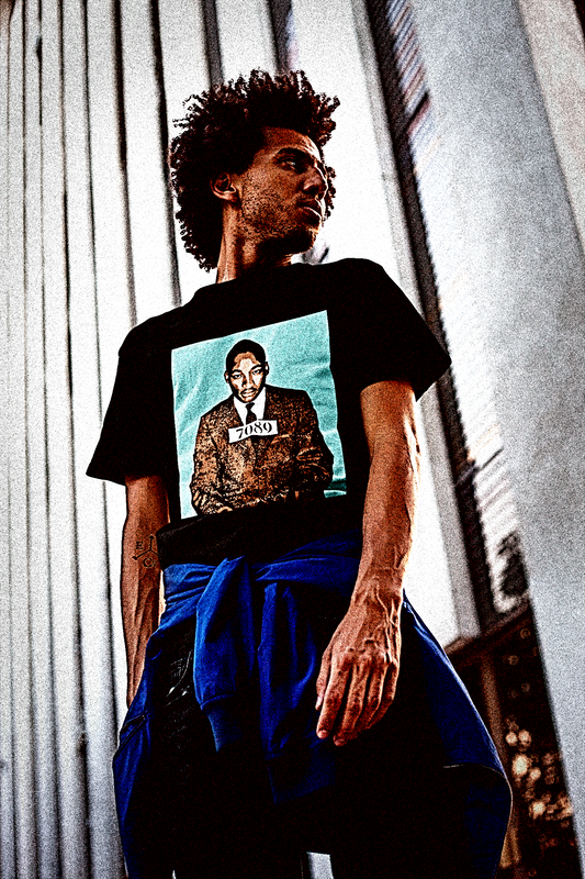 Dude with a loose afro on a city street with a t-shirt of Martin Luther King's Montgomery Mugshot in black, Brown, and blue stencil. 7089