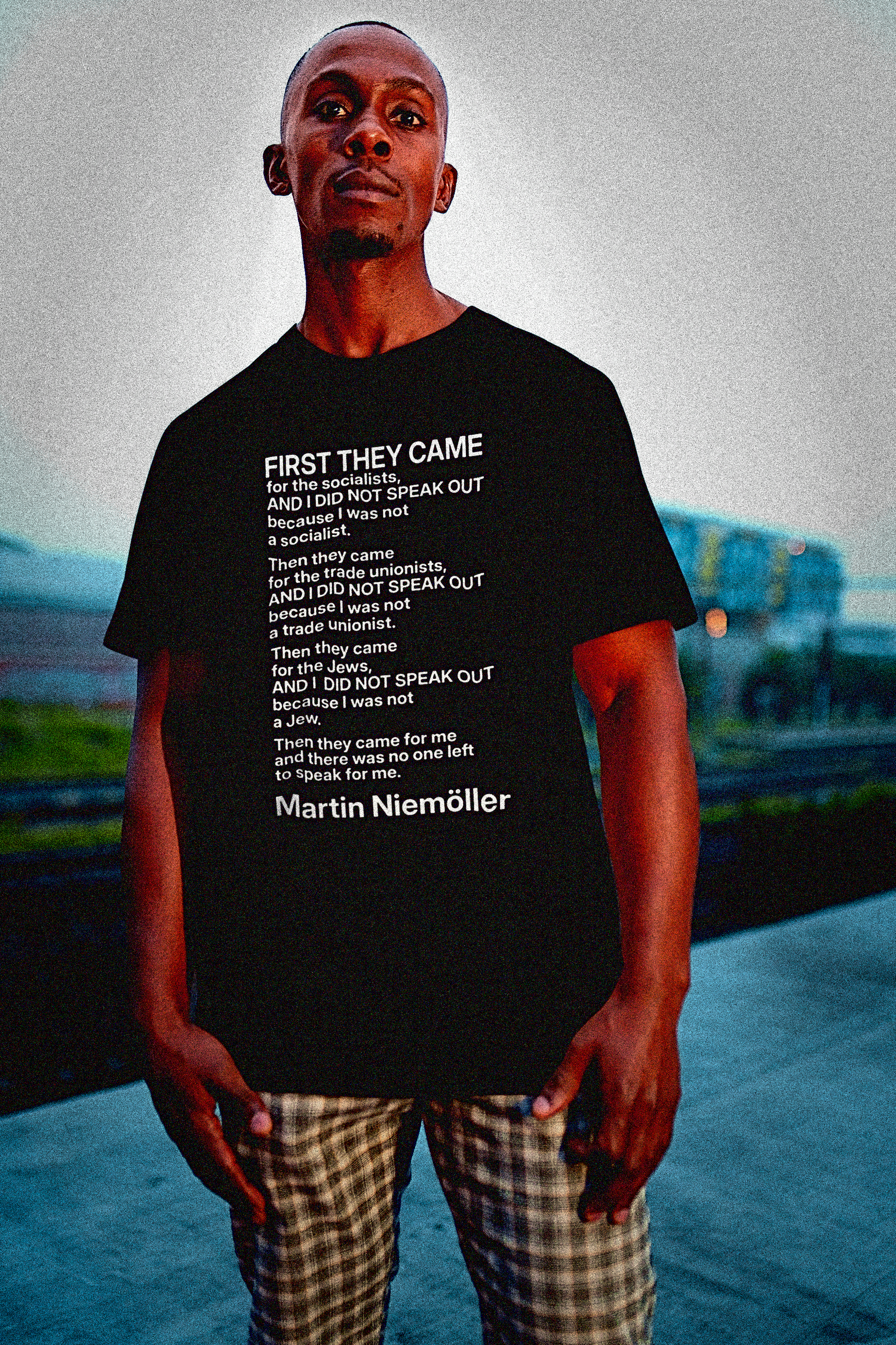 Defiant young Black man on a industrial roof wearing a Basic Black T-Shirt with Martin Niemöller — “First They Came” poem:
German pastor Martin Niemöller (1892–1984) penned his haunting confession “First They Came” after witnessing the rise of Nazism and his own silence during its early years. First they came for the Socialists
And I did not speak out
Because I was not a Socialist
Then they came for the trade unionists
And I did not speak out
Because I was not a trade unionist
Then they came for the Jews
