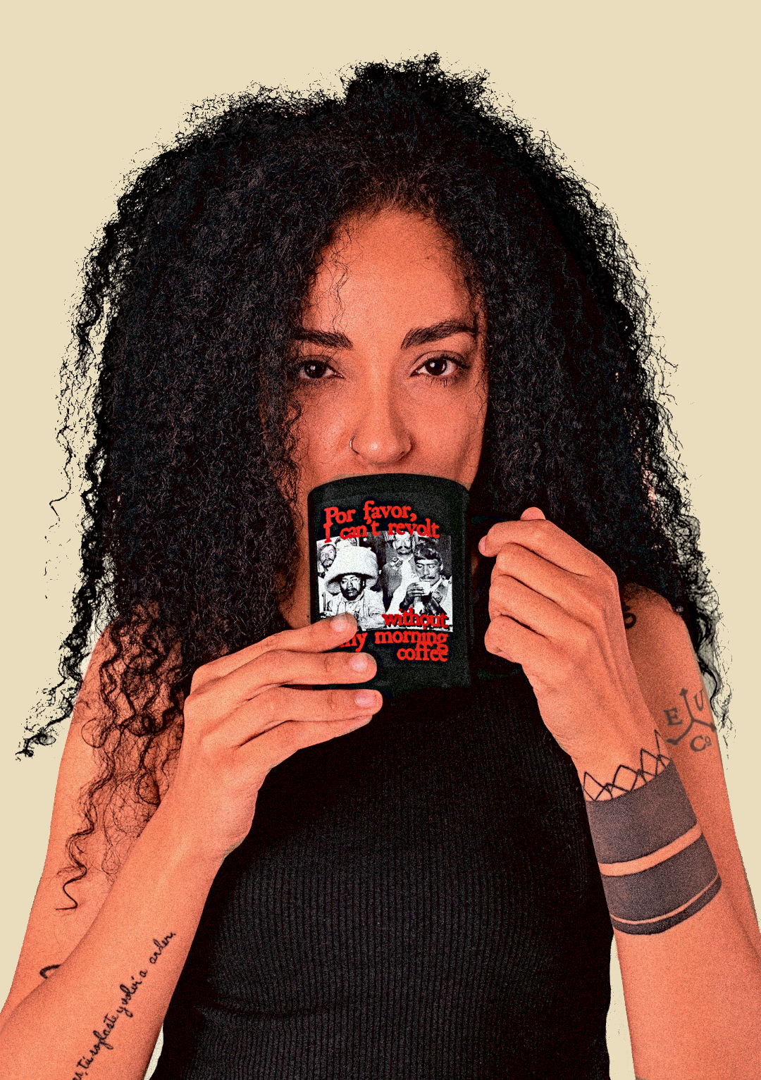 A funky woman with tattoos and black curly hair drinks coffee from a "Por Favor, I can't revolt without my morning coffee" mug featuring Mexican Revolutionaries at Sanborn's. 