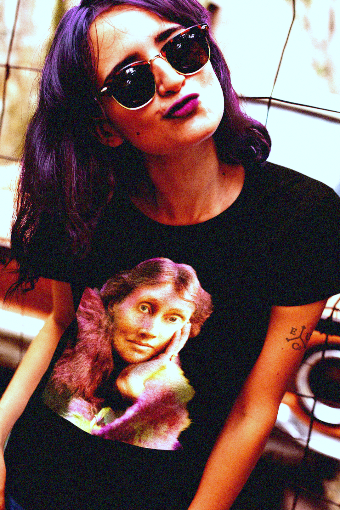 Purple-haired intage chick with vintage glasses in front of a vintage car  wearing a relaxed fit women's tee of a technicolor Virginia Woolf. She made literature new—stream-of-consciousness, fractured time, inner lives spilling across the page. Quality cotton tee. Perfect gift for the lover of literature in your life. Bella+Canvas Women’s Relaxed Tee 6400 #EUTC