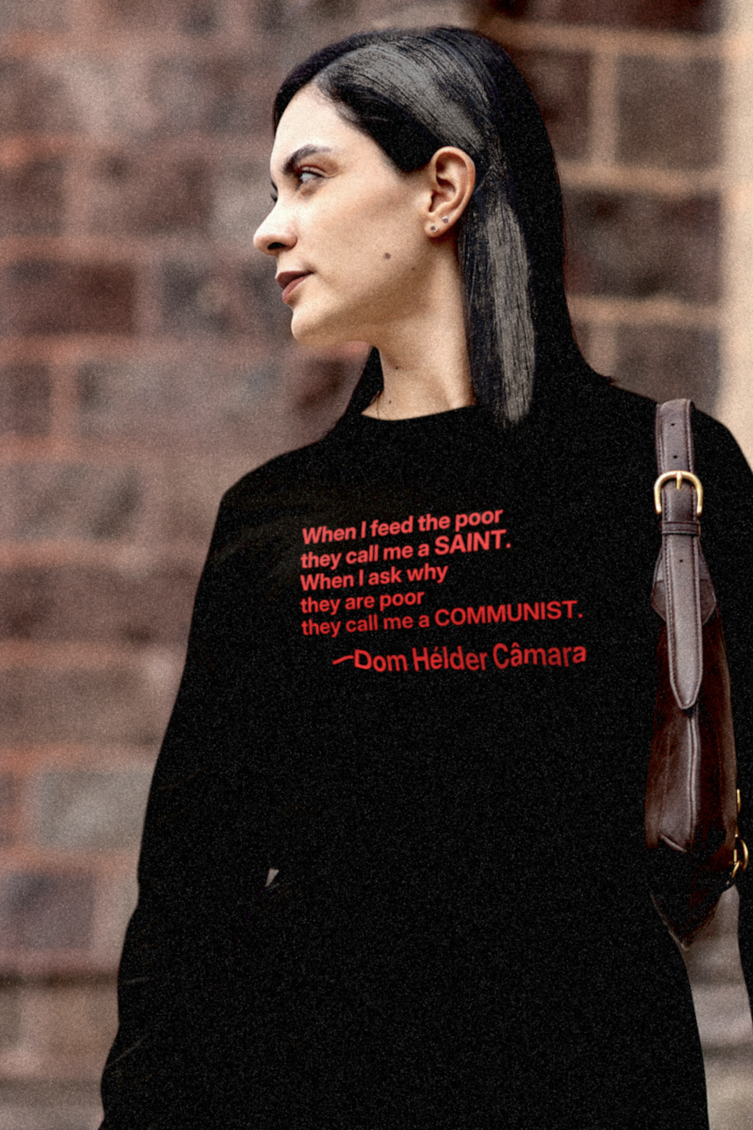 Gothesque Law Student with black white-streaked hair walking across campus wearing a Black Long Sleeve Jersey with the quote 'When I feed the poor they call me a saint. When I ask why they are poor they call me a communist. —Dom Hélder Câmara was a Brazilian Catholic prelate who served as Archbishop of Olinda and Recife from 1964 to 1985 during the military dictatorship in Brazil. Cotton Bella+Canvas 3501 #EUTC