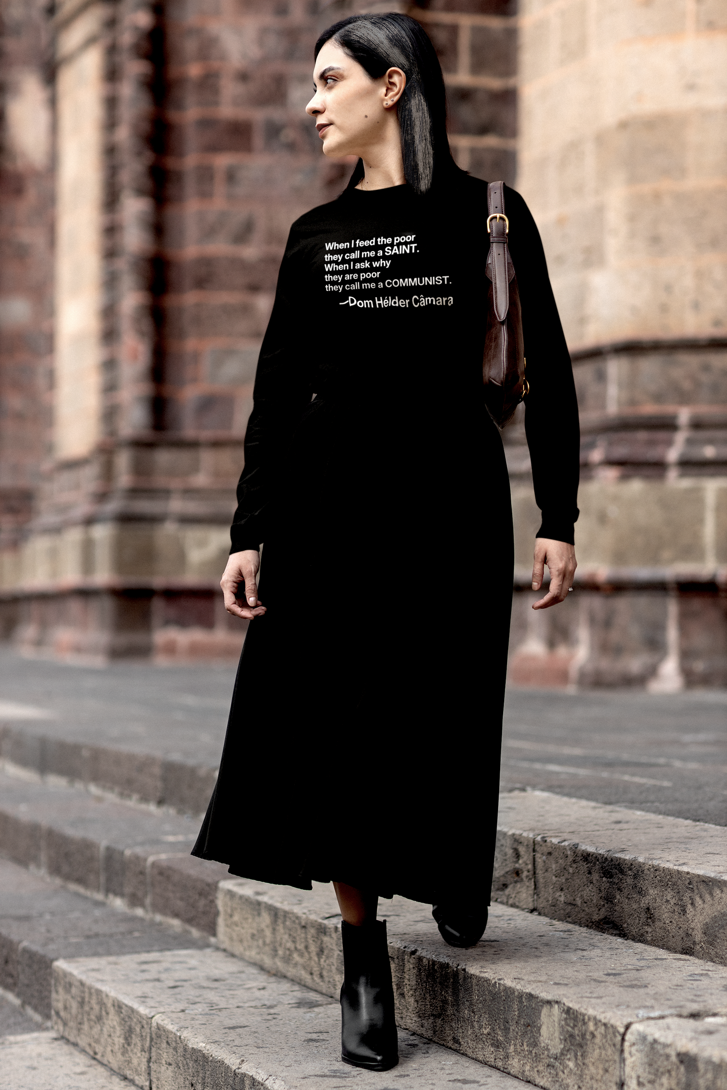 Gothesque Law Student with black white-streaked hair walking across campus wearing a Black Long Sleeve Jersey with the quote 'When I feed the poor they call me a saint. When I ask why they are poor they call me a communist. —Dom Hélder Câmara was a Brazilian Catholic prelate who served as Archbishop of Olinda and Recife from 1964 to 1985 during the military dictatorship in Brazil. Cotton Bella+Canvas 3501 #EUTC