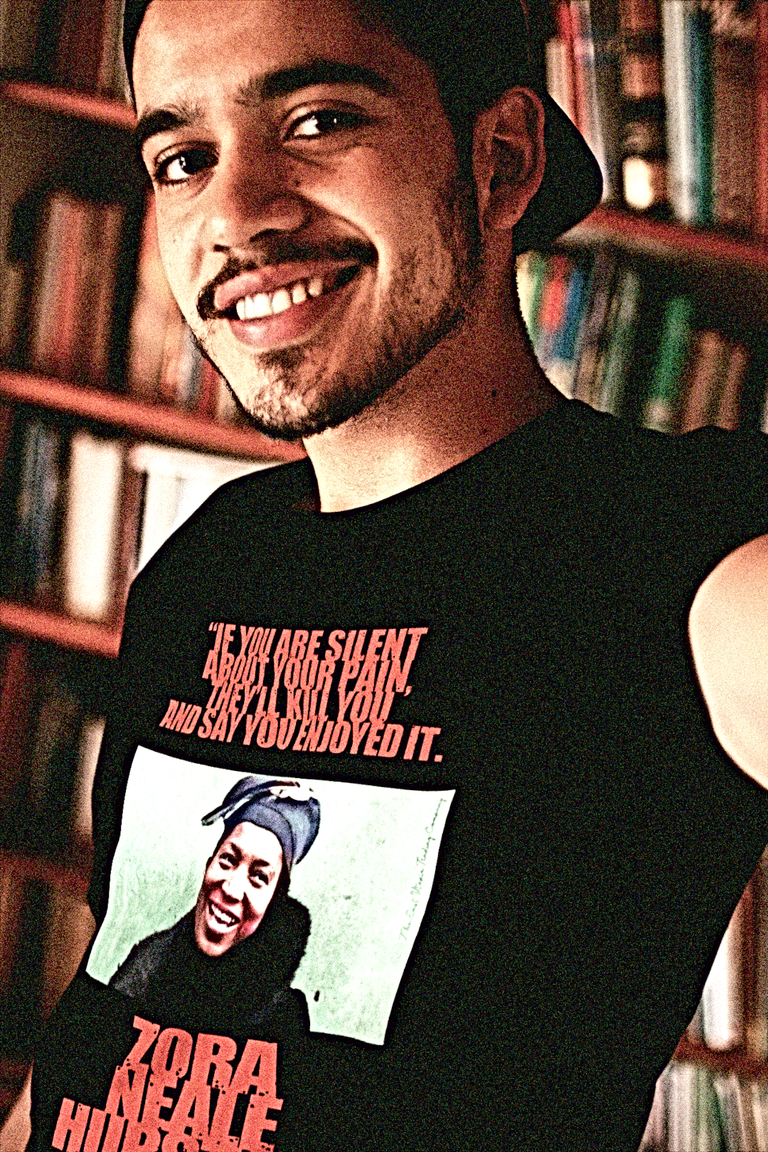 Zora Neale Hurston - Basic T-Shirt - Young Man in a Library wearing a basic Black t-shirt depicting Zora Neale Hurston: If you are silent about your pain, they'll kill you and say you enjoyed it. Zora Neale Hurston didn’t just write novels; she bottled the rhythm and brilliance of Black life in the South and poured it straight onto the page. Cotton Bella+Canvas 3001  #EUTC
