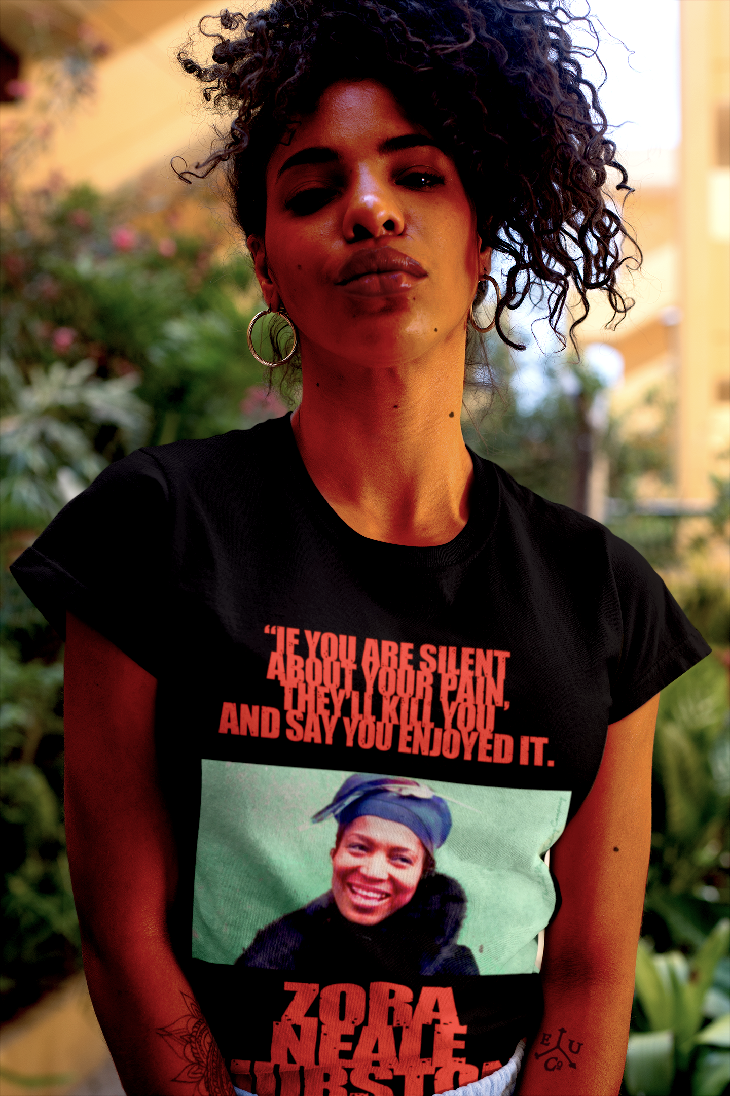 Proud Black woman with kinky natural afro in a garden wearing Black Relaxed Fit Women's T-Shirt: Zora Neale Hurston "If you are silent about your pain, they'll kill you and say you enjoyed it.”

Zora Neale Hurston didn’t just write novels; she bottled the rhythm and brilliance of Black life in the South and poured it straight onto the page. Cotton Bella+Canvas 6400 #EUTC